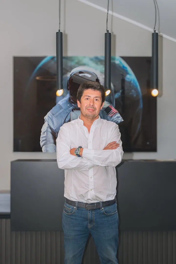 Director Ejecutivo con brazos cruzados y mural espacial de fondo con iluminación